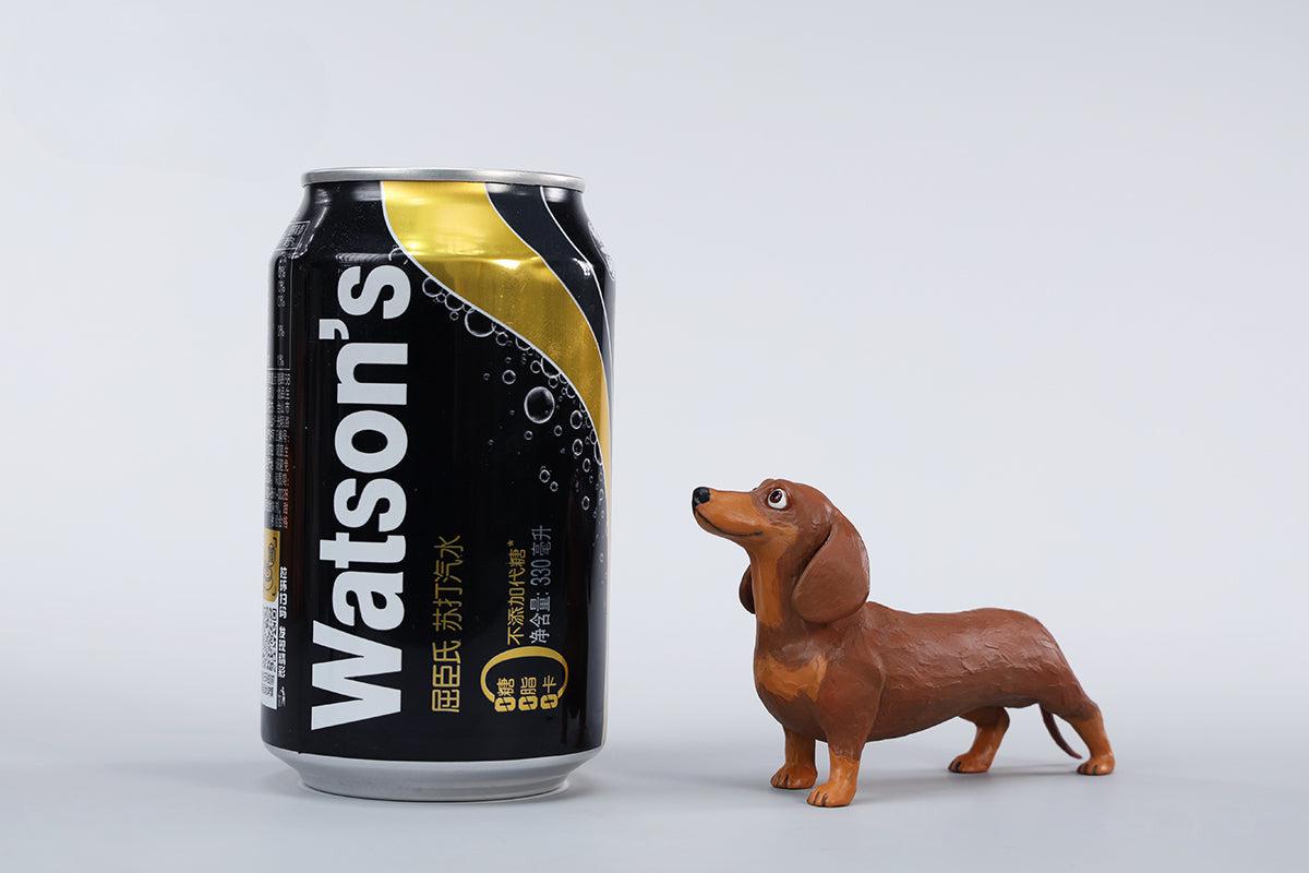 Two small clay Dachshund dog models, one black and one brown, captured in a realistic and lifelike manner. The models showcase detailed features, including expressive eyes and realistic fur textures. Perfect for collectors and dog enthusiasts.