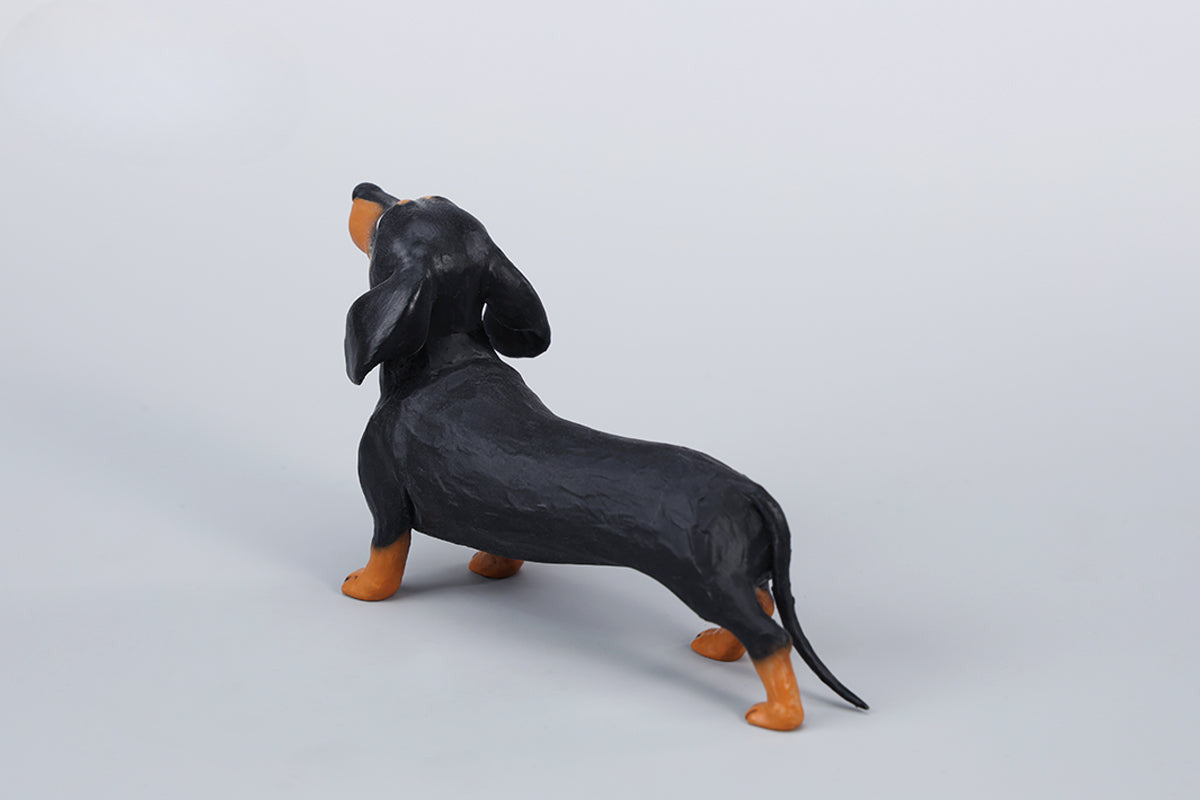 Two small clay Dachshund dog models, one black and one brown, captured in a realistic and lifelike manner. The models showcase detailed features, including expressive eyes and realistic fur textures. Perfect for collectors and dog enthusiasts.