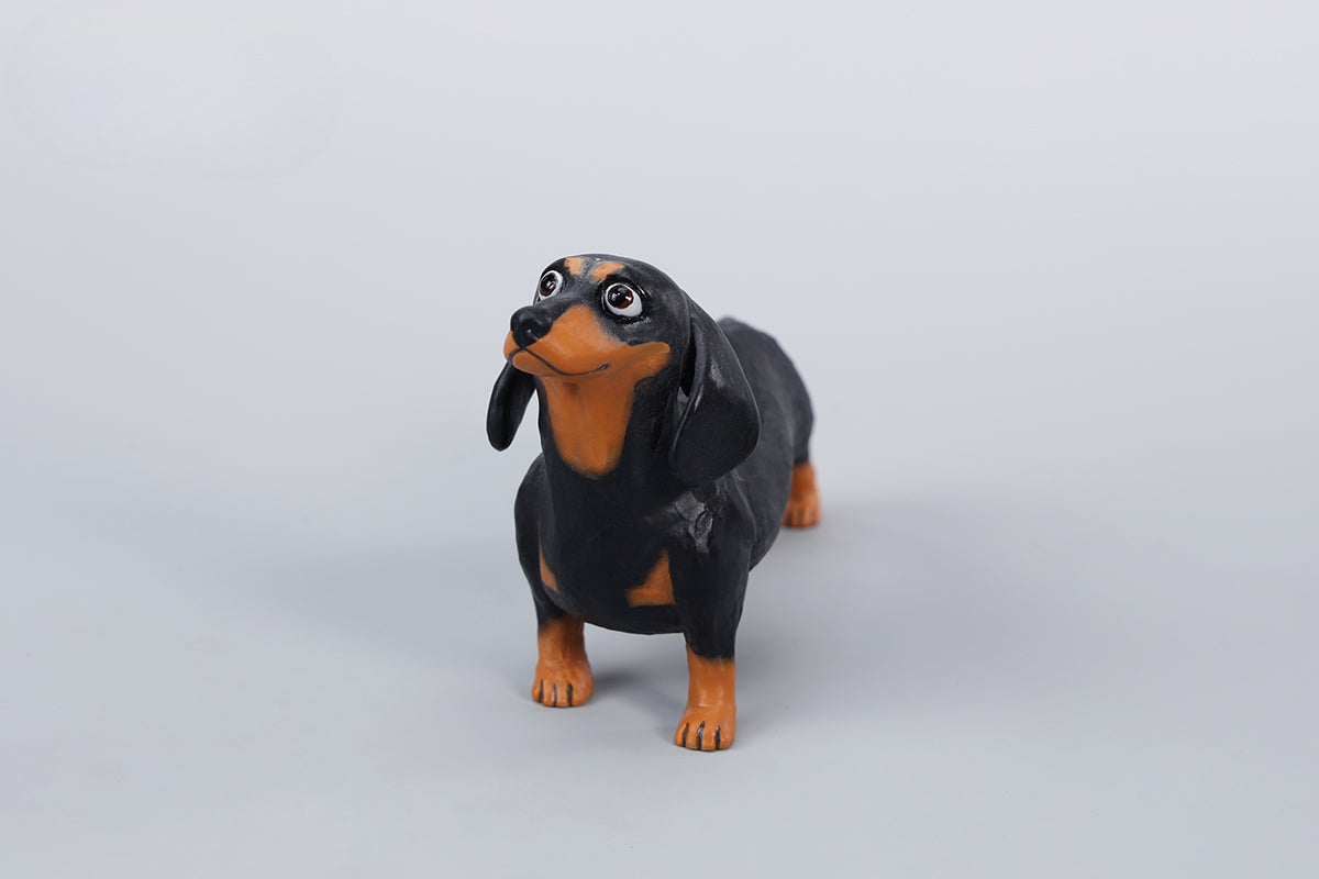 Two small clay Dachshund dog models, one black and one brown, captured in a realistic and lifelike manner. The models showcase detailed features, including expressive eyes and realistic fur textures. Perfect for collectors and dog enthusiasts.