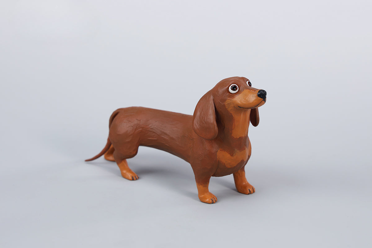 Two small clay Dachshund dog models, one black and one brown, captured in a realistic and lifelike manner. The models showcase detailed features, including expressive eyes and realistic fur textures. Perfect for collectors and dog enthusiasts.