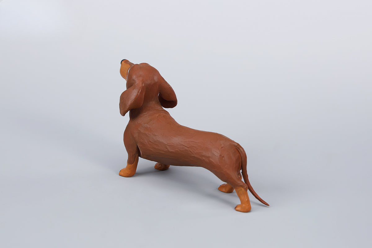 Two small clay Dachshund dog models, one black and one brown, captured in a realistic and lifelike manner. The models showcase detailed features, including expressive eyes and realistic fur textures. Perfect for collectors and dog enthusiasts.