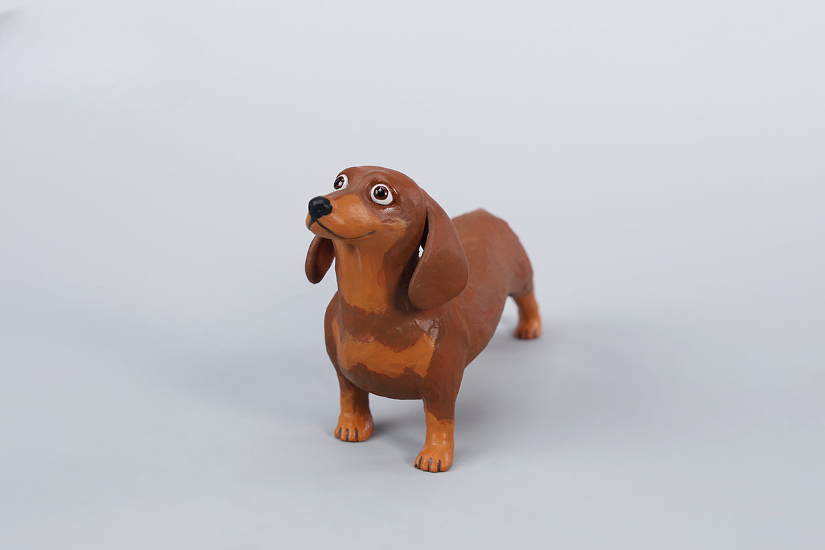 Two small clay Dachshund dog models, one black and one brown, captured in a realistic and lifelike manner. The models showcase detailed features, including expressive eyes and realistic fur textures. Perfect for collectors and dog enthusiasts.