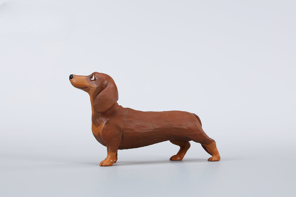 Two small clay Dachshund dog models, one black and one brown, captured in a realistic and lifelike manner. The models showcase detailed features, including expressive eyes and realistic fur textures. Perfect for collectors and dog enthusiasts.