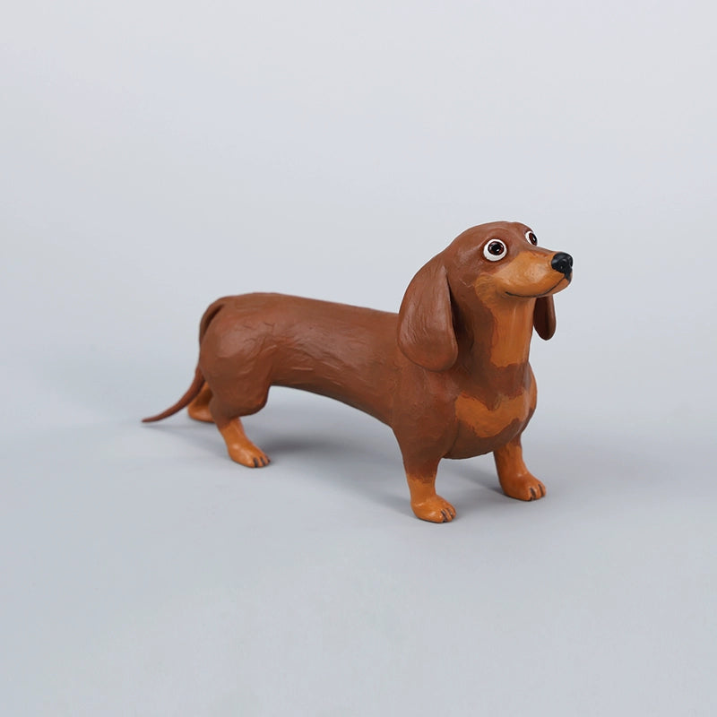 Two small clay Dachshund dog models, one black and one brown, captured in a realistic and lifelike manner. The models showcase detailed features, including expressive eyes and realistic fur textures. Perfect for collectors and dog enthusiasts.