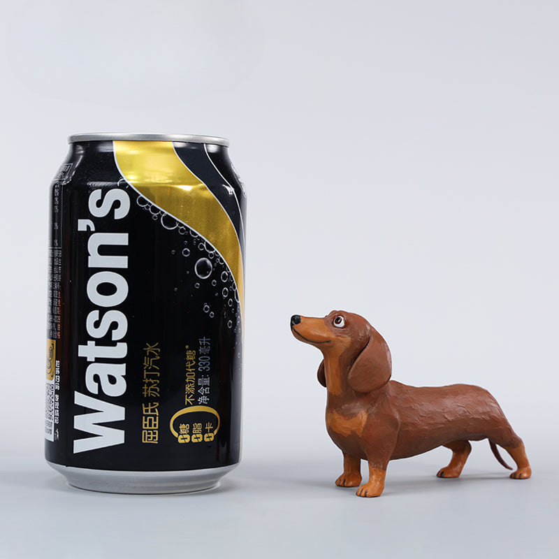 Two small clay Dachshund dog models, one black and one brown, captured in a realistic and lifelike manner. The models showcase detailed features, including expressive eyes and realistic fur textures. Perfect for collectors and dog enthusiasts.