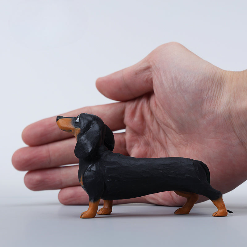 Two small clay Dachshund dog models, one black and one brown, captured in a realistic and lifelike manner. The models showcase detailed features, including expressive eyes and realistic fur textures. Perfect for collectors and dog enthusiasts.