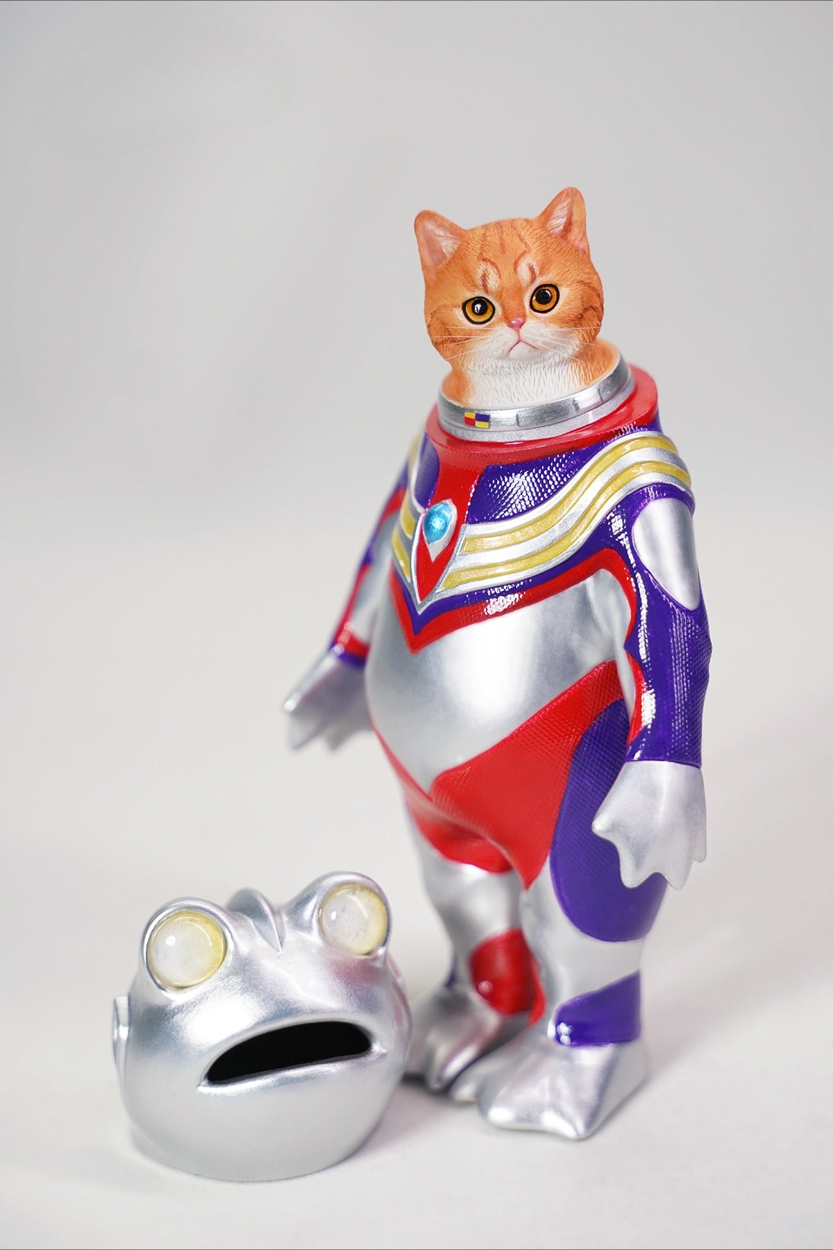 This Ultrafrog action figure features a frog body with a removable cat head sculpture, made of durable vinyl. The figure measures 9 x 5 x 16 cm and includes a magnetic headpiece that can rotate, making it a fun and customizable collectible for fans of unique hybrid figures, superheroes, and creative designs.