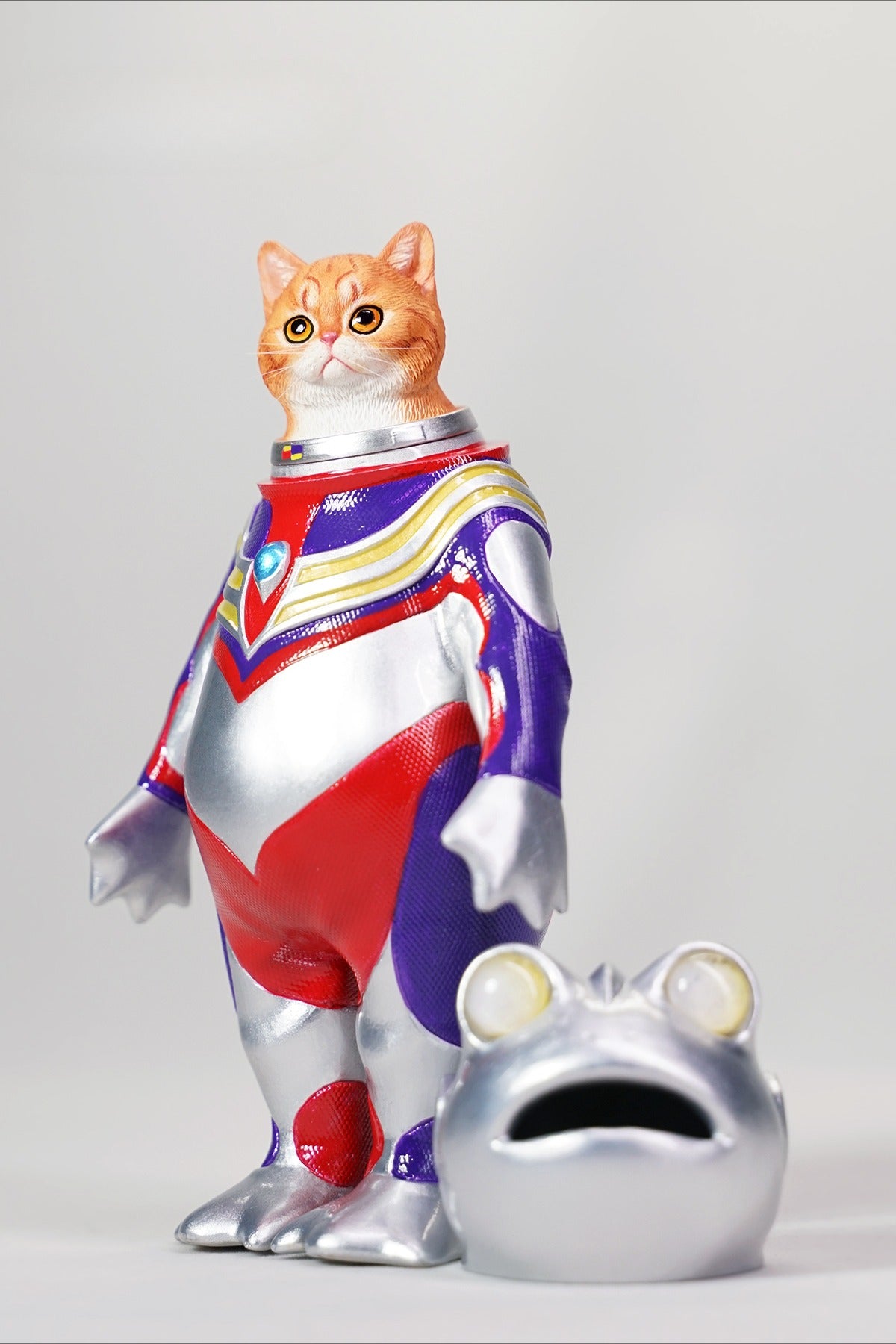 This Ultrafrog action figure features a frog body with a removable cat head sculpture, made of durable vinyl. The figure measures 9 x 5 x 16 cm and includes a magnetic headpiece that can rotate, making it a fun and customizable collectible for fans of unique hybrid figures, superheroes, and creative designs.