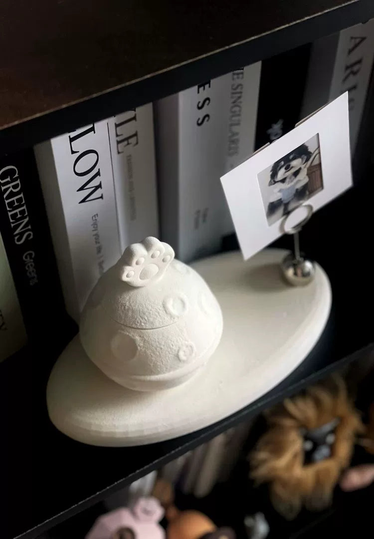 This white moon paw ceramic pet urn features a unique moon-shaped design with a paw print lid and detachable photo frame, measuring 22cm wide and 8cm tall with a 1-2cm base, holding 250ml of ashes. Perfect for North American pet owners honoring small pets like cats or dogs, it offers secure storage and a personalized memorial display for shelves or tables.