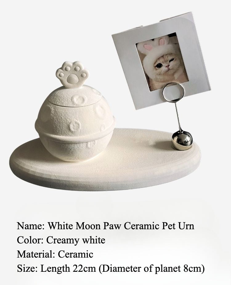 This white moon paw ceramic pet urn features a unique moon-shaped design with a paw print lid and detachable photo frame, measuring 22cm wide and 8cm tall with a 1-2cm base, holding 250ml of ashes. Perfect for North American pet owners honoring small pets like cats or dogs, it offers secure storage and a personalized memorial display for shelves or tables.