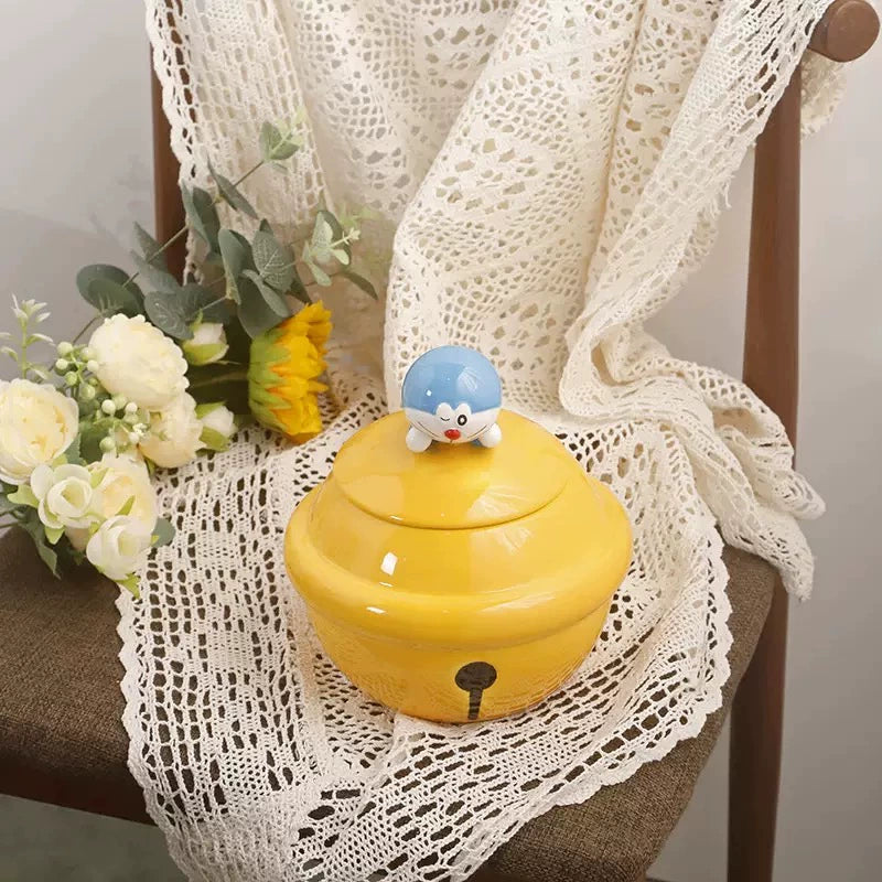Yellow ceramic Doraemon pet cremation urn with a glossy finish, featuring a round shape and a cute Doraemon figure on top, ideal for North American pet owners. This handcrafted urn provides secure ashes storage, perfect for home memorial display on mantels or shelves, with a vibrant yellow hue and playful design.