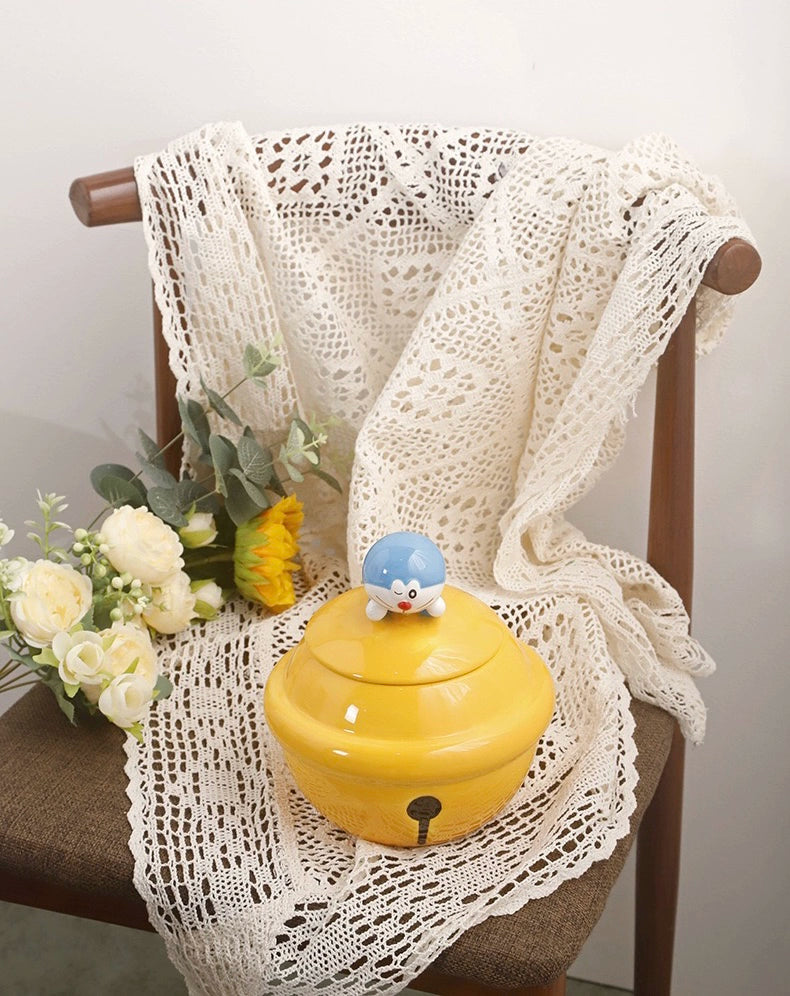 Yellow ceramic Doraemon pet cremation urn with a glossy finish, featuring a round shape and a cute Doraemon figure on top, ideal for North American pet owners. This handcrafted urn provides secure ashes storage, perfect for home memorial display on mantels or shelves, with a vibrant yellow hue and playful design.