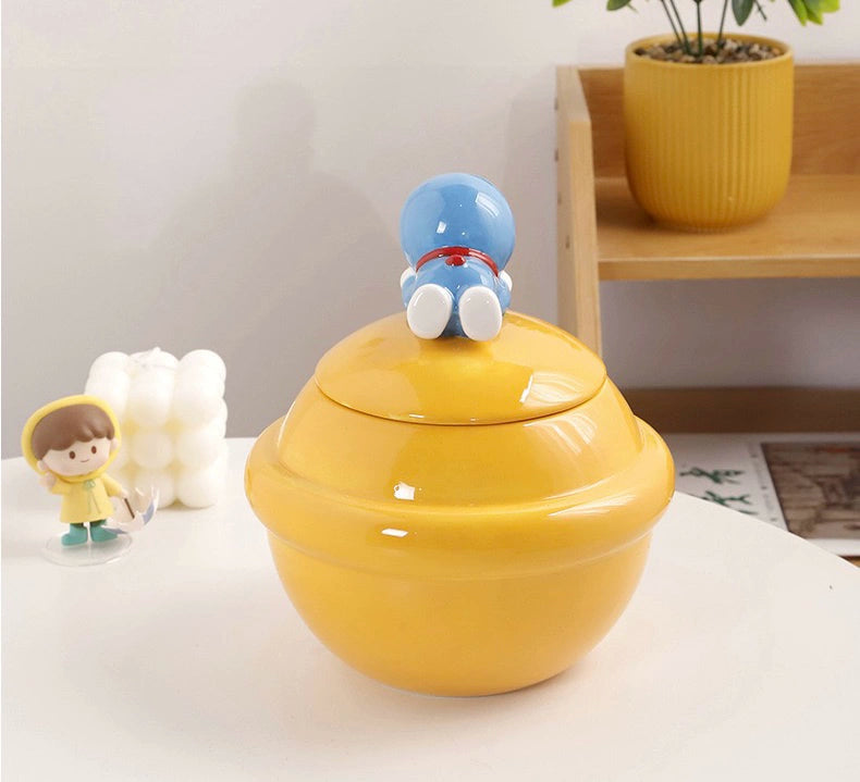 Yellow ceramic Doraemon pet cremation urn with a glossy finish, featuring a round shape and a cute Doraemon figure on top, ideal for North American pet owners. This handcrafted urn provides secure ashes storage, perfect for home memorial display on mantels or shelves, with a vibrant yellow hue and playful design.